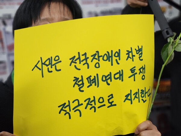 '시민은 전국장애인차별철폐연대 투쟁 적극적으로 지지한다' 종이 피켓을 든 모습.ⓒ전국장애인차별철폐연대