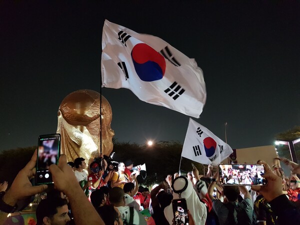 카타르월드컵 당시 우리 대표팀의 16강 진출 확정 후 16강의 성지가 된 에듀케이션시티 스타디움 주변의 피파컵 조형물에서 한국팬들과 외국팬들이 기쁨을 함께 나누는 모습. ⓒ이원무