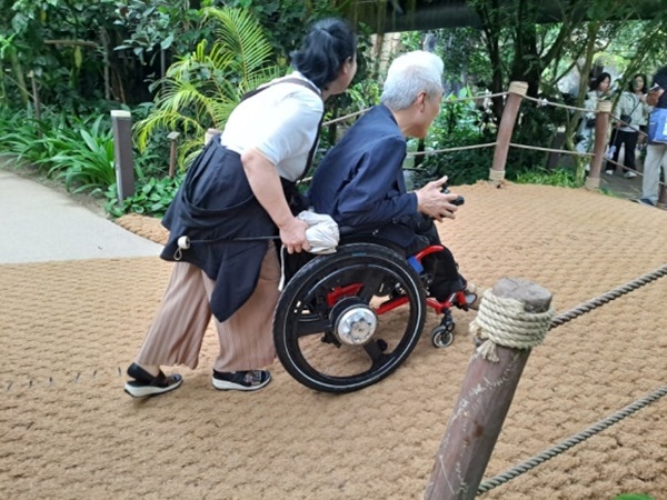 휠체어를 밀어주는 자원봉사자. ⓒ이복남