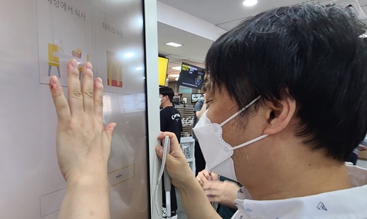 2022년 7월 11일 오전 11시 30분경, 서울 중구 한 패스트푸드점에서 열린 시각장애인권리보장연대의 ‘내돈내산 권리찾기 캠페인’ 모습. 한 시각장애인이 키오스크를 클릭해 주문하려했지만 실패하고 있다.ⓒ에이블뉴스DB