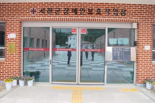 서천군 장애인보호작업장 주출입문은 터치식자동문 1곳으로 앞바닥에 점자블록이 설치돼 있어 휠체어를 사용하는 장애인이 불편을 겪을 것으로 보였다. 터치식자동문이나 자동문 2곳을 설치하고, 한곳의 앞바닥에 점자블록을 설치하면 모두 불편 없이 이용할 수 있다. 주출입문 옆에는 시각장애인이 손끝으로 만져 건물 내부를 알 수 있는 점자안내판, 앞바닥에 점자블록이 양호하게 설치됐다. ©박종태