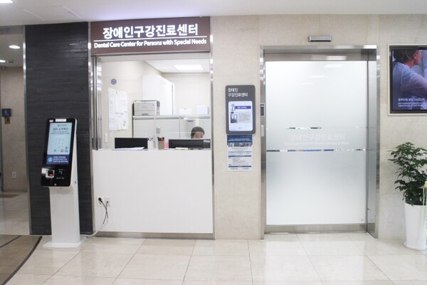 장애인구강진료센터 출입문 터치식자동문으로 설치가 되여 손이 불편 하거나 횔체어사용장애인들 출입을 하기가 편리 하지만 터치식 버튼이 높아 횔체어사용장애인들 불편하다. 안내데스크 및 접수 창구는 턱이 높고 밑에 공간이 없어 횔체어사용장애인들 불편하다 .키오스크는 시각장애인이 이용을 못할 뿐만 아니라 높이가 높고 밑에 휠체어가 들어갈 공간이 마련돼 있지 않았다.
