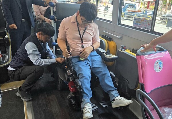 저상버스 운전기사가 휠체어에 좌석 고정벨트를 채우고 있는 장면.ⓒ부산시