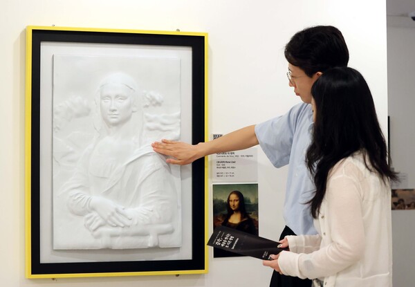 시각장애인을 위한 어두운 미술관 전시에 AI·3D프린팅 기술로 재현된 '모나리자'를 일반 관람객들이 실제로 만지며 감상하고 있다.ⓒ유니원커뮤니케이션즈