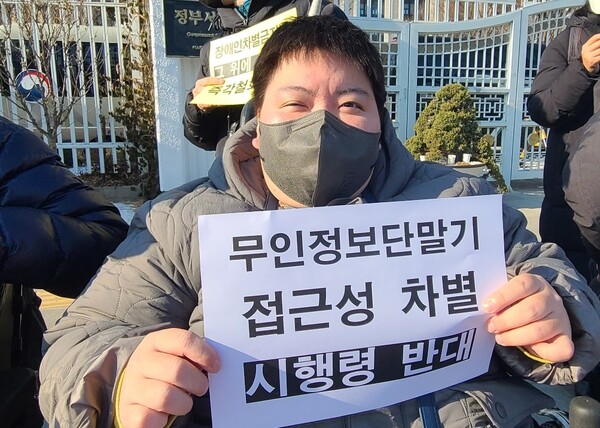 장애인차별금지추진연대(장추련) 등 9개 단체가 2022년 12월 29일 정부서울청사 앞에서 기자회견을 갖고, 입법예고가 종료된 ‘장애인차별금지법 시행령 일부개정’을 전면 재검토할 것을 촉구했다. ‘무인정보단말기 접근권 차별 시행령 반대’ 피켓을 든 활동가 모습.ⓒ에이블뉴스DB