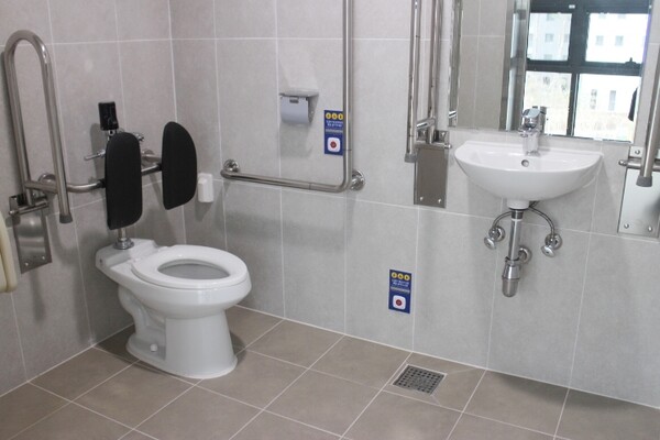 광주광역시 운암복합문화체육센터 남녀장애인화장실 내부는 대변기에 자동 물 내림 센서와 등받이가 설치됐으며, 비상호출벨과 휴지걸이는 대변기에 앉았을 때 손이 닿는 곳에 위치해 있다. 세면대 양쪽 손잡이는 휠체어 접근을 용이하게 하는 상하가동식인데, 세면대 밑에 배관 구조물이 있어 휠체어 접근을 방해할 것으로 보였다. ©박종태