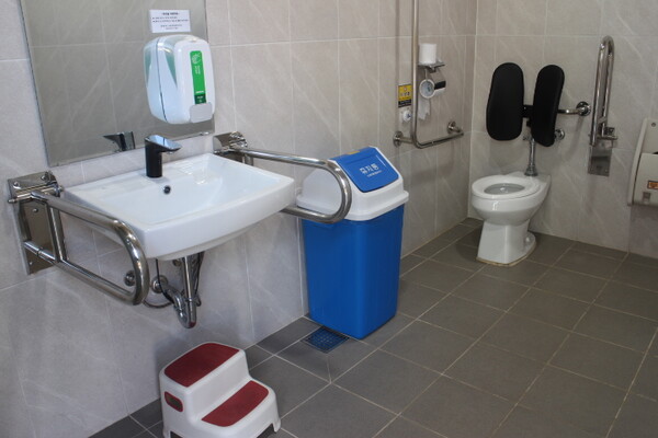 광주시립수목원 남녀장애인화장실 내부는 대변기에 자동 물 내림 센서가 설치됐지만, 등받이는 등을 받쳐 주기에는 조금 높은 위치에 설치됐다. 비상호출벨과 휴지걸이는 대변기에 앉았을 때 손이 닿는 곳에 위치해 있다. 세면대 양쪽 손잡이는 휠체어 접근을 용이하게 하는 상하가동식인데, 세면대 밑에 배관 구조물이 있어 휠체어 접근을 방해할 것으로 보였다. ©박종태