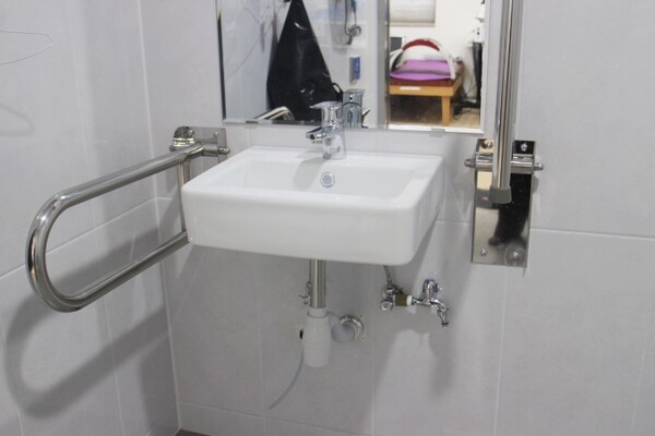 창촌보건진료소 남여장애인화장실 내부 세면대 양쪽 손잡이는 휠체어의 세면대 접근을 용이하게 하는 상하가동식인 반면, 세면대 밑에 구조물이 있어 휠체어를 사용하는 장애인이 수도꼭지에 접근하는데 어려움이 따른다. ©박종태