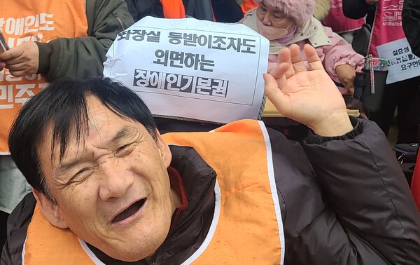 장애인차별금지추진연대(장추련)가 노들장애인자립생활센터, 김예지·서미화 의원과 함께 16일 "장애인화장실의 불편한 좌변기 등받이로 차별을 겪고 있다"며 국가인권위원회에 진정을 제기했다. 기자회견에 참석한 중증장애인 활동가 뒤에 '화장실 등받이조차도 외면하는 장애인기본권'이라는 종이 피켓이 있다.ⓒ에이블뉴스