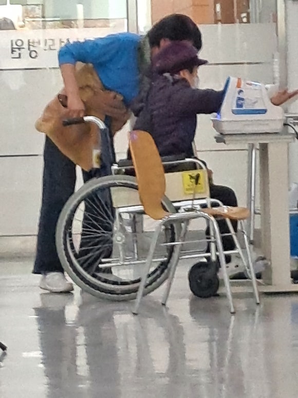 수동휠체어를 타고 혈압을 재는 사람. ⓒ이복남